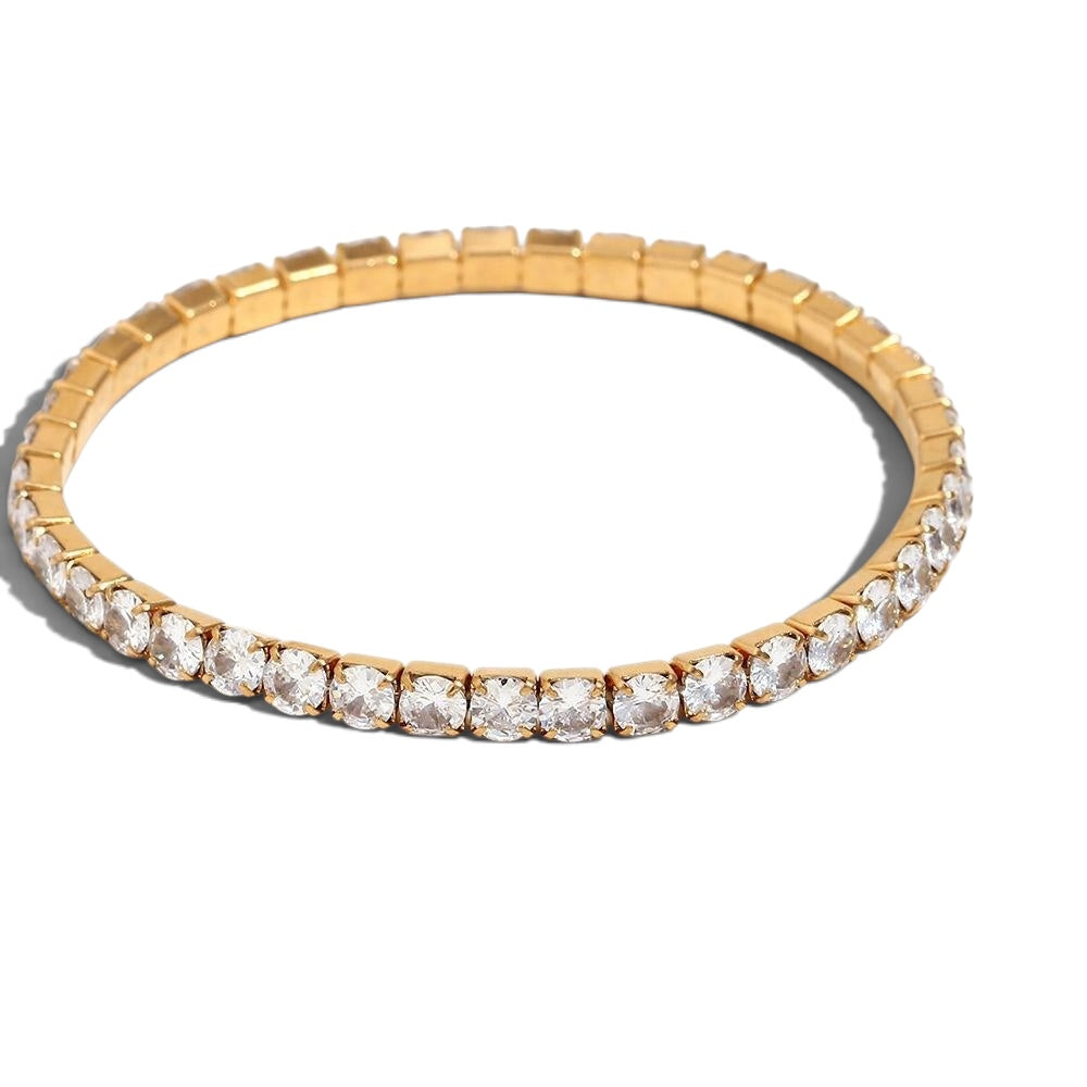 A gold tennis bracelet featuring a row of clear round-cut gemstones in a prong setting, displayed on a clean white background.