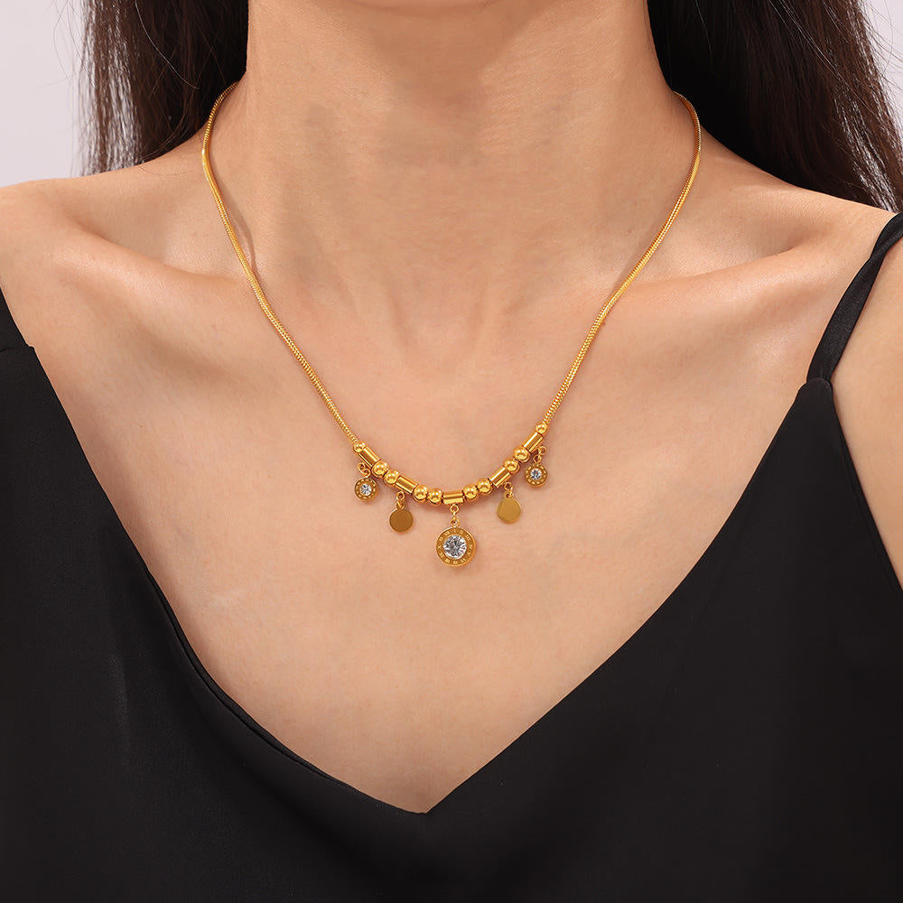 Gold necklace with charms on a model wearing a black top