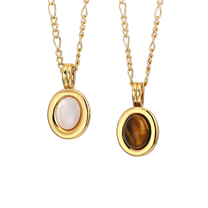 Two gold oval pendant necklaces on chains, one with a smooth pale pink mother-of-pearl center and the other with a brown tiger's eye stone, shown against a plain white background.