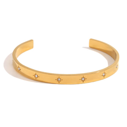 A gold open cuff bracelet featuring five small starburst motifs set with clear stones, photographed on a clean white background.