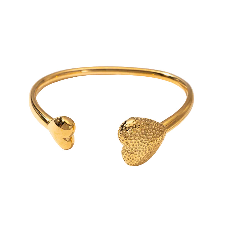 A gold-plated open cuff bracelet with one polished smooth heart-shaped end and one textured, dimpled heart-shaped end, shown on a clean white background.